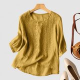 Aurora yellow embroidered blouse on a neutral grey background