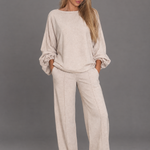 Beige long-sleeve top and straight-leg trouser co-ord on a model against a grey studio background.