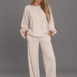 Beige long-sleeve top and straight-leg trouser co-ord on a model against a grey studio background.
