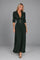 Dua York model wearing the dark-green Elvira pleated maxi dress with four gold buttons against a grey studio background