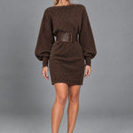 Dua York model wearing the chocolate-brown Felicity knitted mini dress with wide belt against a grey studio background
