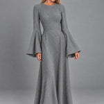 Dua York model wearing the grey Selene floor-length dress with bell sleeves against a grey studio background